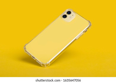Yellow IPhone 11 In Clear Silicone Case Back View Falling Down Isolated On A Yellow Background. Transparent Phone Case Mock Up