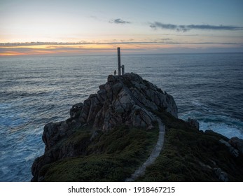 Yellow jacket person standing at metal structure viewpoint at the tip of Cabo Prior lighthouse steep rocky cliff shore coast Ferrol Galicia Spain