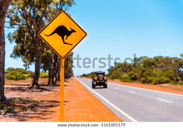 Yellow kangaroo sign on\
Australian country road. Warning sign for kangaroos crossing the\
road