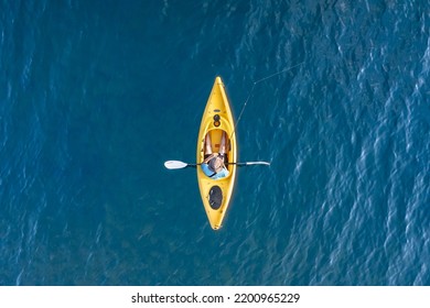 Yellow Kayak In Blue Lake Water With Man Fishing Overhead Aerial