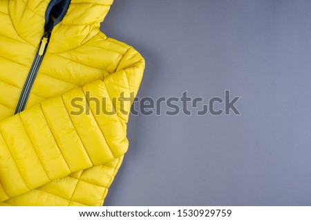 Yellow kids winter jacket composition on yellow background. Flat lay, layout and tabletop mockup with copy space.