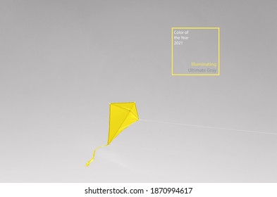 A yellow kite soars in a cloudless gray sky. Illuminating and Ultimate Gray. Colors of the year 2021. The trendy concept of freedom, summer hobbies, entertainment in nature. Minimalism, copy space.