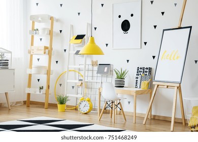 Yellow Lamp In Bright School Nursery With Toys And Easel Next To Desk With White Chair