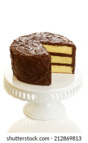 A Yellow Layer Cake With Chocolate Icing With A Slice Missing