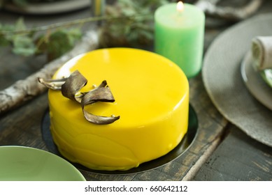 yellow lemon cake on the wooden table with green plates and decorative candles