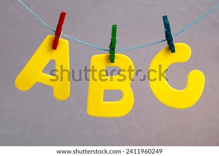 Yellow letters A, B and C attached to rope with clothespins