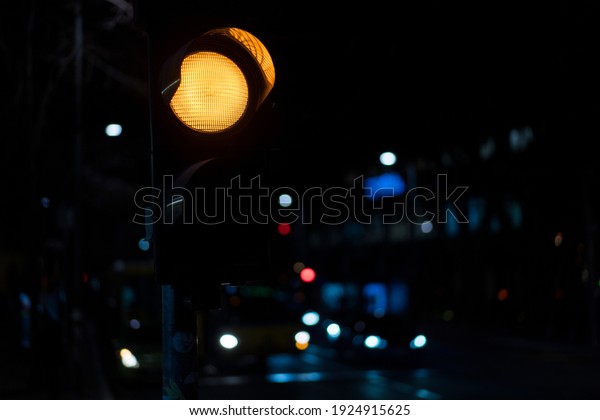 Yellow light on the traffic lights turned\
on, with nighttime city scene in the\
background