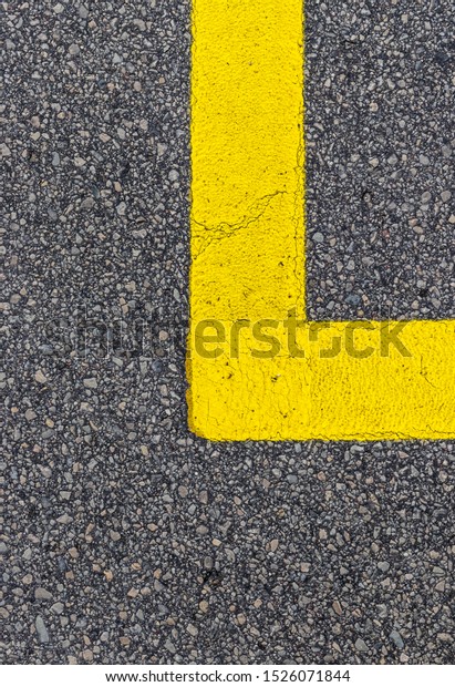 Yellow line. Band of\
yellow reflective paint on a black asphalt. Yellow line on road\
texture. Road marking.