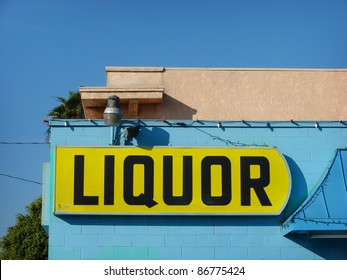 Yellow Liquor Store Sign On Side Of Blue Building