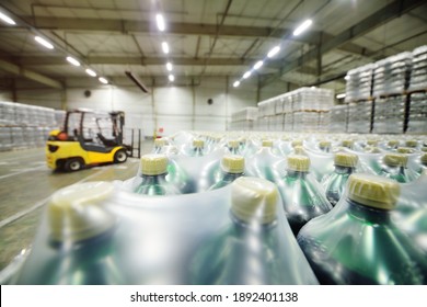 Yellow Loader On The Background Of A Huge Industrial Food Warehouse With Plastic PET Bottles With Beer, Water, Drinks.