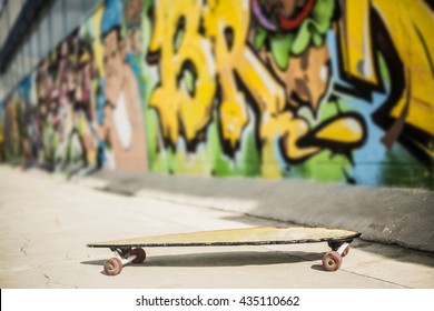 Yellow Longboard Near The Concrete Grafiti  Wall In Perspective. No People. 