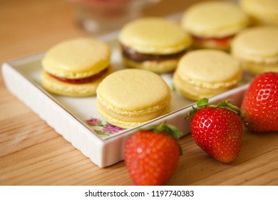 Yellow Macarons from french recipes dessert with strawberry yam filling. Traditional french macarons in a rows on a food pan.                   