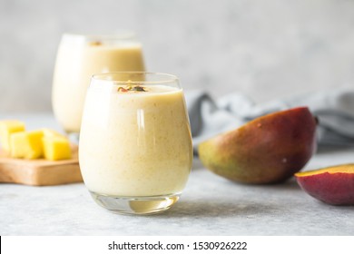 Yellow mango yogurt or smoothie on blue background . Turmeric Lassie or lassi in two glasses.