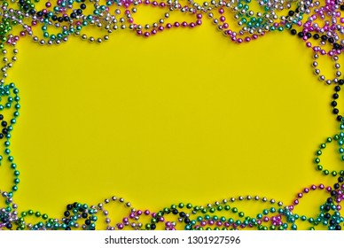 Yellow Mardi Gras background bordered with colored bead necklaces with room for text.
