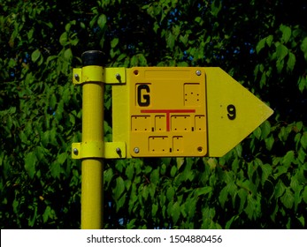 Yellow Marker Sign On Steel Pipe Post Indicating Underground Gas Line At A Certain Distance. Signs And Symbols Concept. Bright Yellow Signage With Red Lines And Black Lettering. Energy Supply Theme.