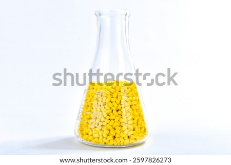 Yellow masterbatch granules in Erlenmeyer flask isolated on white background, color pigment carrier polymer in plastic industry. Perfect for plastic company catalog design