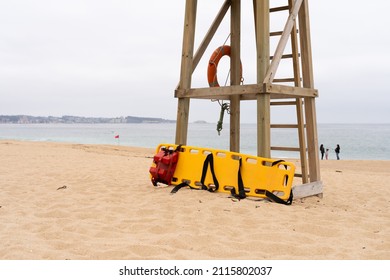Yellow medical backboard leaning on wooden lifeguard tower on cloudy day in Algarrobo beach, Chile