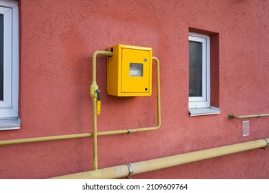 Yellow Metal Anti Vandal Box With Natural Gas Meter Gauge And Pipeline On The Wall. Gas Distribution For Heating Apartments In Winter.
