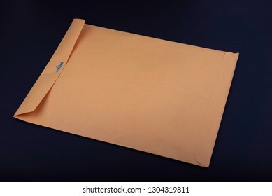 Yellow Metal Clasp Envelope On Dark Blue Surface. 