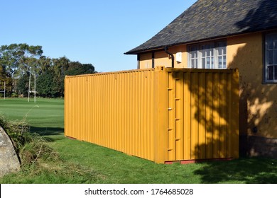 Yellow Metal Shipping Container Beside Building In Field