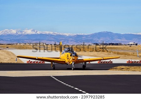 Yellow Military Trainer Airplaner Taxiing with the Rocky Mountains in the Background