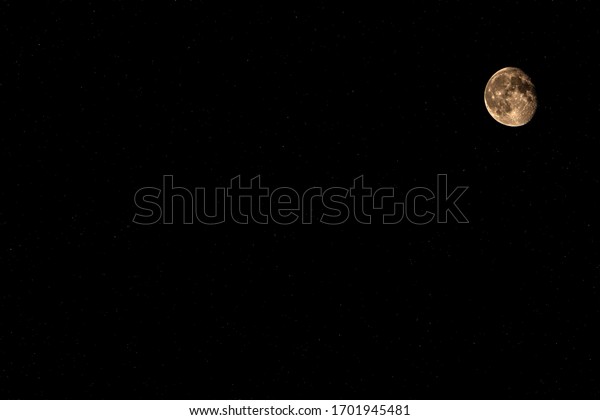 Yellow moon against a starry sky with a place for\
the inscription. A real photograph. Part of the moon is illuminated\
by the sun in space.