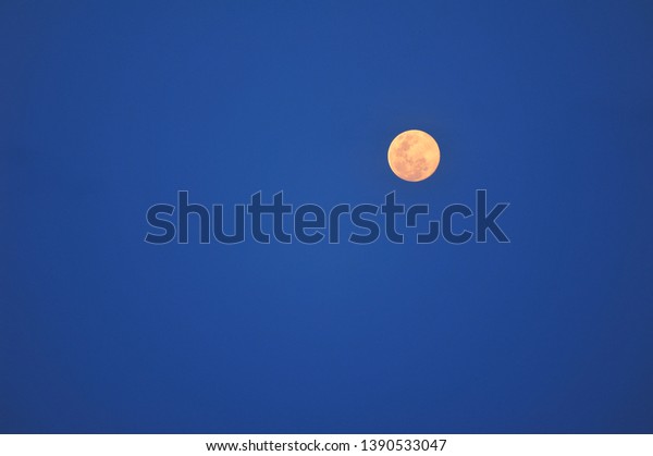 Yellow moon in blue\
sky.