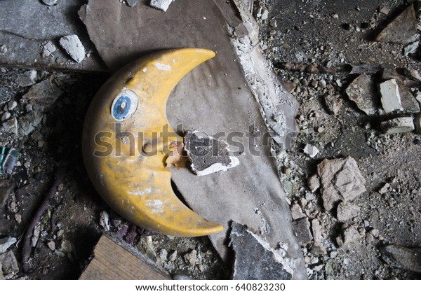 Yellow moon of plastic on dirty floor with\
pieces of joke and\
concrete