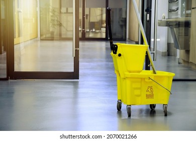 Yellow Mop Bucket And Mop Prepared For Floor Cleaning.