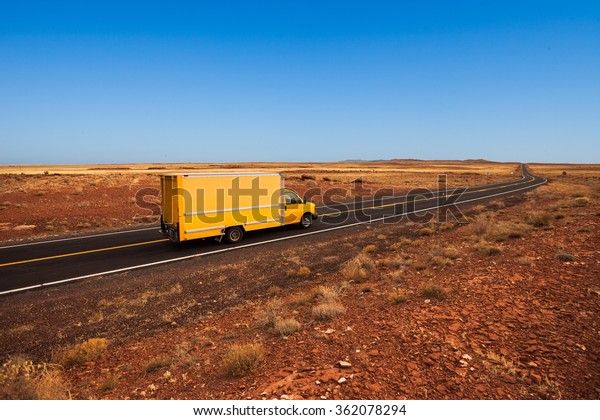 Yellow moving\
truck on desert highway,\
Arizona