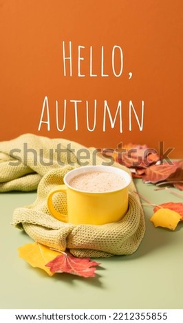 Yellow mug with hot drink tea coffee on bright background with an autumn leaf and text Hello autumn