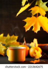 A Yellow Mug Of Hot Tea Or Coffee On A Wooden Table. Maple Branch With Yellow Leaves, Small Pumpkins. Thanksgiving Greeting Card