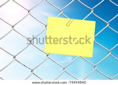 yellow note on chain link fence see blue sky