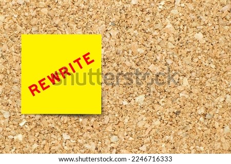 Yellow note paper with word rewrite on cork board background with copy space