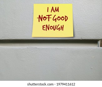 Yellow note stick on copyspace wall I AM NOT GOOD ENOUGH (cross out NOT) , means building self-esteem ,to love respect yourself unconditionally, stop seeking others approval,embrace flaws imperfection