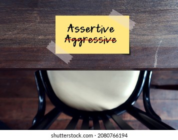 Yellow note stick on table with text written AGGRESSIVE, changed to ASSERTIVE - concept of standing up for oneself but not violate another person. Be direct, honest, express opinion without humiliate 