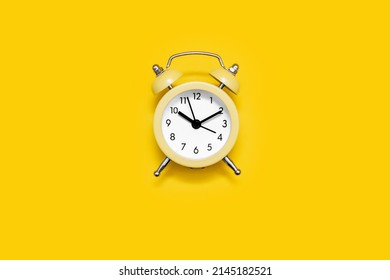 Yellow old-fashioned alarm clock with a dial on a yellow background. The concept of time and responsibility. Vintage look of the alarm clock