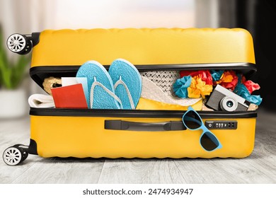 a yellow open suitcase with things lying on the floor in the living room. travel concept - Powered by Shutterstock