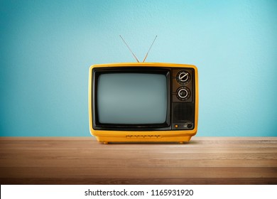 Yellow Orange color old vintage retro Television on wood table with mint blue background . - Shutterstock ID 1165931920
