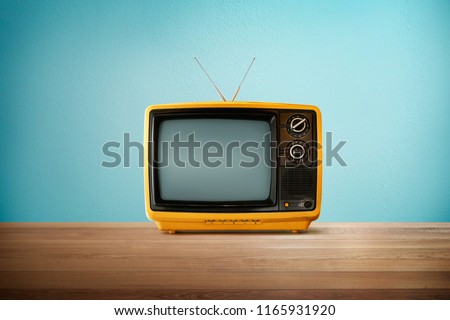 Yellow Orange color old vintage retro Television on wood table with mint blue background .