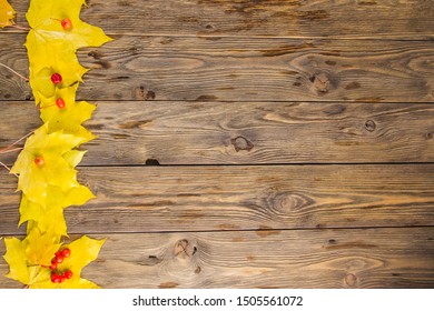 Yellow And Orange Fallen Maple Leaves With Red Tiny Apples And Ashberry On Dark Brown Wood Table Background. Fall And Autumn Concept