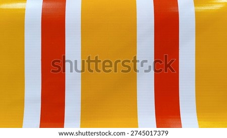 Yellow and Orange Striped Pattern


Description: A straightforward, close-up photograph of a bright, graphic striped pattern on a textured, plastic-like fabric. The pattern consists of equal-width vertical stripes of golden-yellow, warm orange, and bright white. The fabric has a visible woven plastic grid texture, suggesting a material like a tarp or an outdoor awning. The colors are highly saturated, and the pattern fills the frame symmetrically.