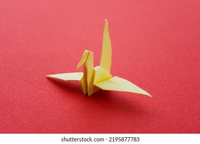 Yellow Origami Paper Crane On Red Background.