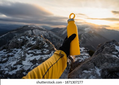 Yellow Outdoor Travel Water Bottle. Male Hand Holding Bottle. Mountains And Winter In National Park In During Sunset. Travel Concept, Drink Water, Adventure  