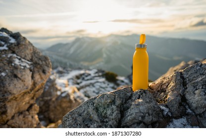 Yellow outdoor travel water bottle. Male hand holding bottle. Mountains and winter in national park in during sunset. Travel concept, drink water, adventure   - Shutterstock ID 1871307280