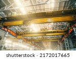 Yellow overhead or beam or bridge cranes in industrial metalworking factory