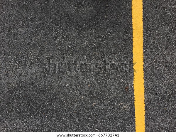 Yellow paint line on black\
asphalt road surface texture. space transportation\
background