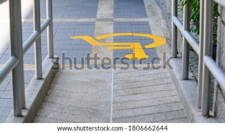 Yellow painted handicapped sign traffic symbol on the floor in front of ramp way for support wheelchair