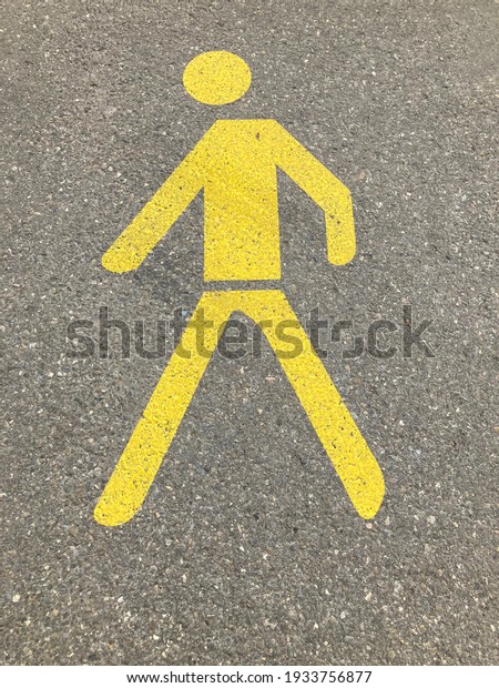 Yellow painted pedestrian crossing sign or\
pathway sign on asphalt in\
Switzerland