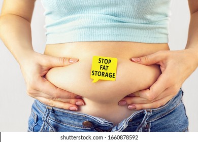 A yellow paper blank message is written Stop fat storage on belly with hands squeezes at the waistline of a young woman in jeans. The concept of excess weight, weight loss, diet, obesity, junk food. - Shutterstock ID 1660878592